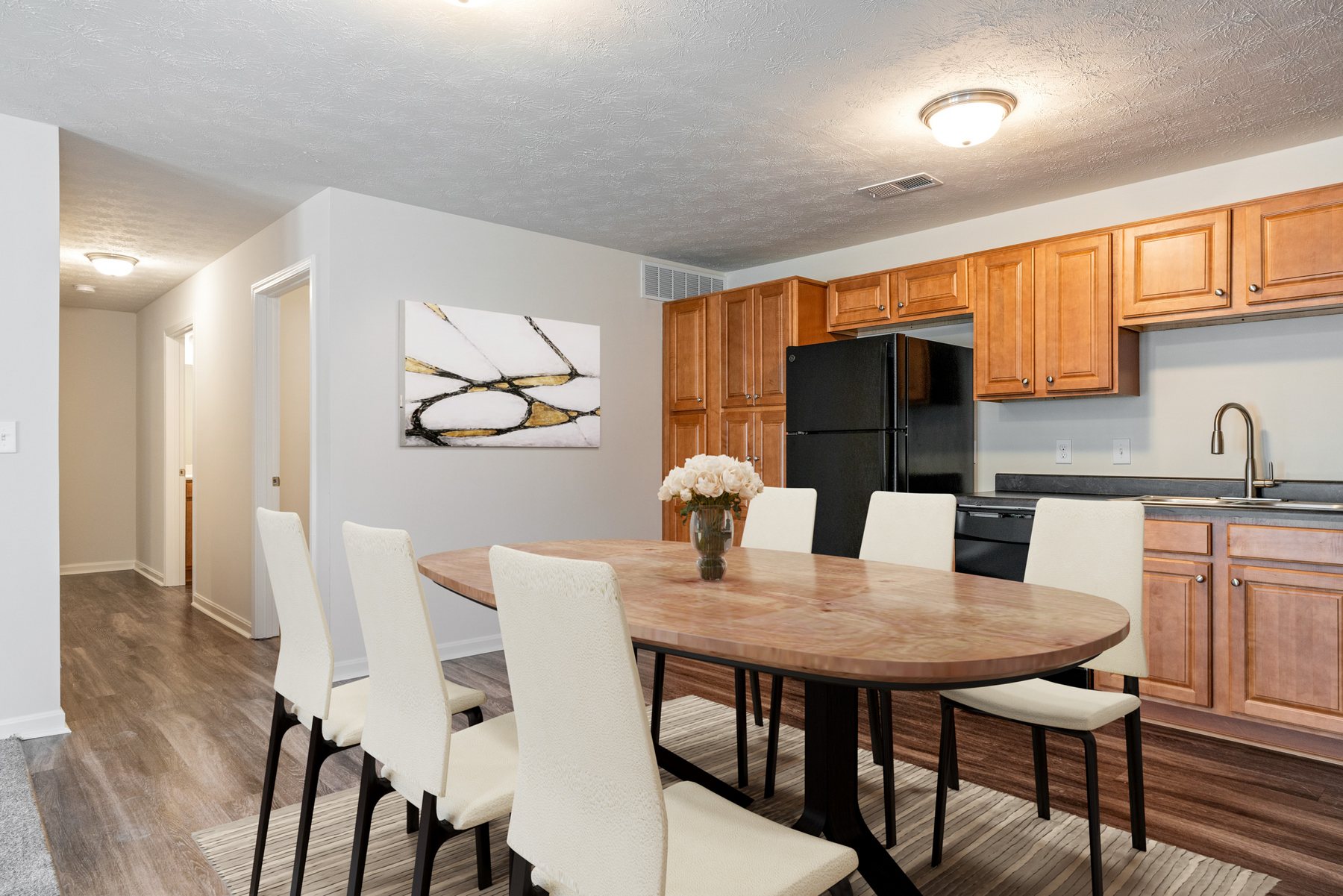 Kitchen and dining area with wood cabinets, black appliances, and a full dining set in a Cane Run Station home